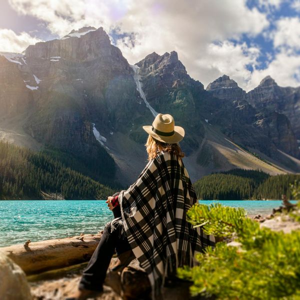Person meditating peacefully outdoors near calm water.